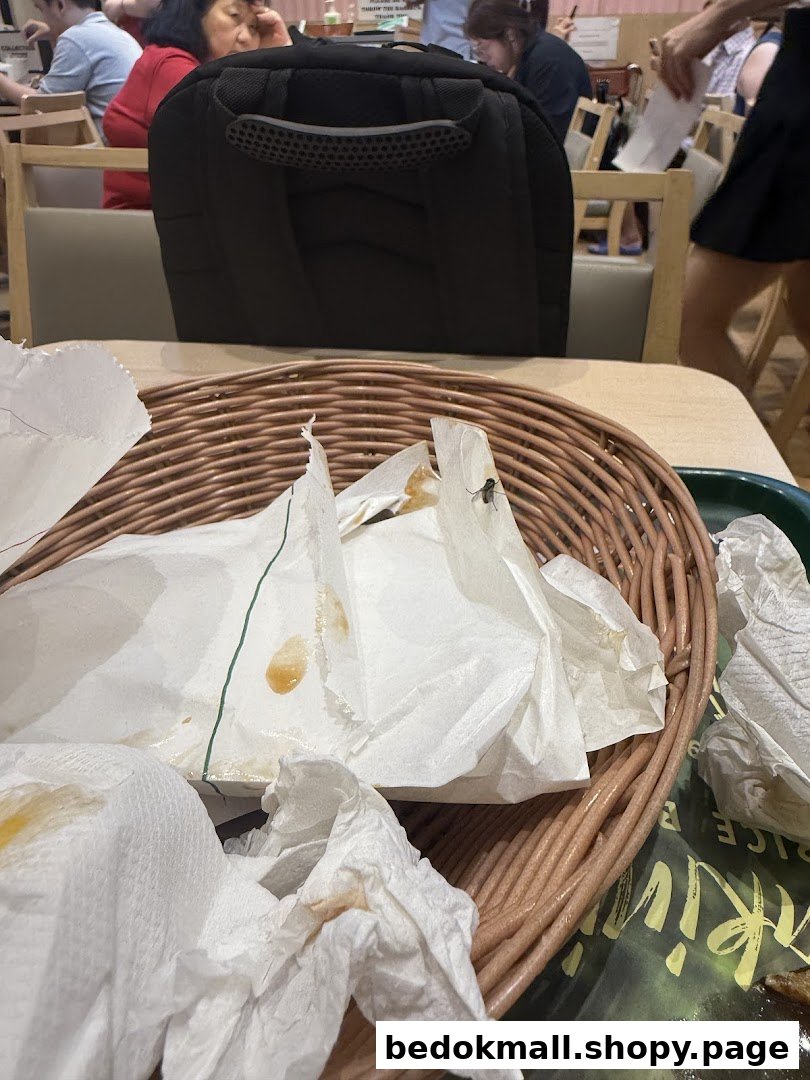 A wicker basket with used napkins and wrappers on a table inside a restaurant.