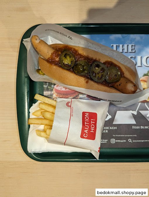 A hot dog with jalapeños and fries on a green tray from MOS Burger.