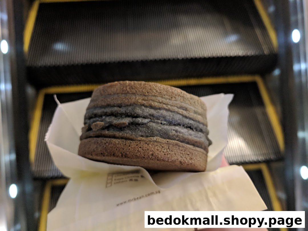A round food item in a wrapper held near escalators.