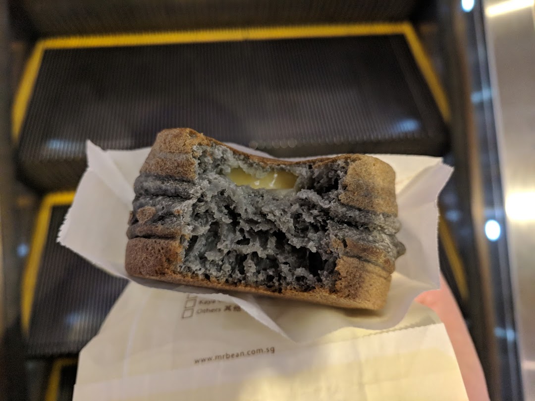 Partially eaten food item with creamy filling held near an escalator.