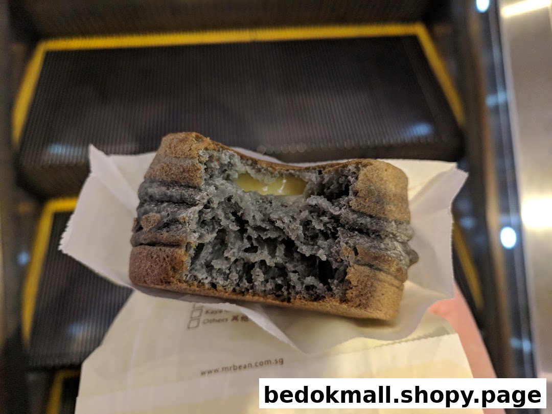 Partially eaten food item with creamy filling held near an escalator.