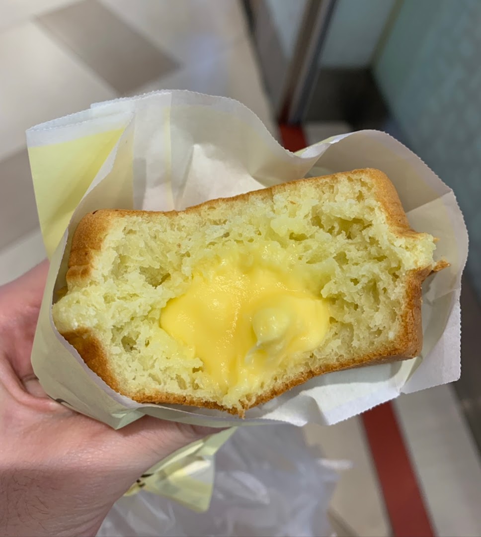 Hand holding a baked good with creamy yellow filling.