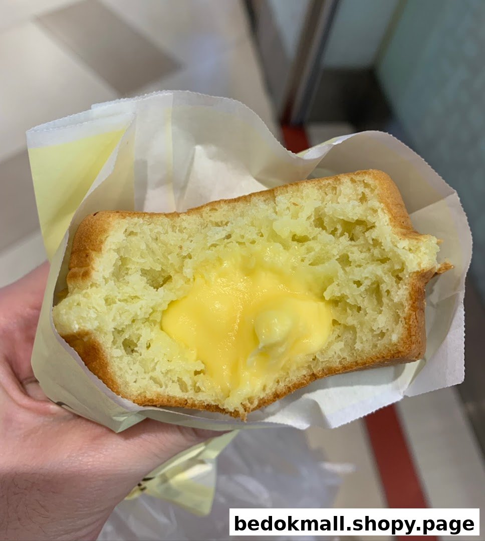 Hand holding a baked good with creamy yellow filling.