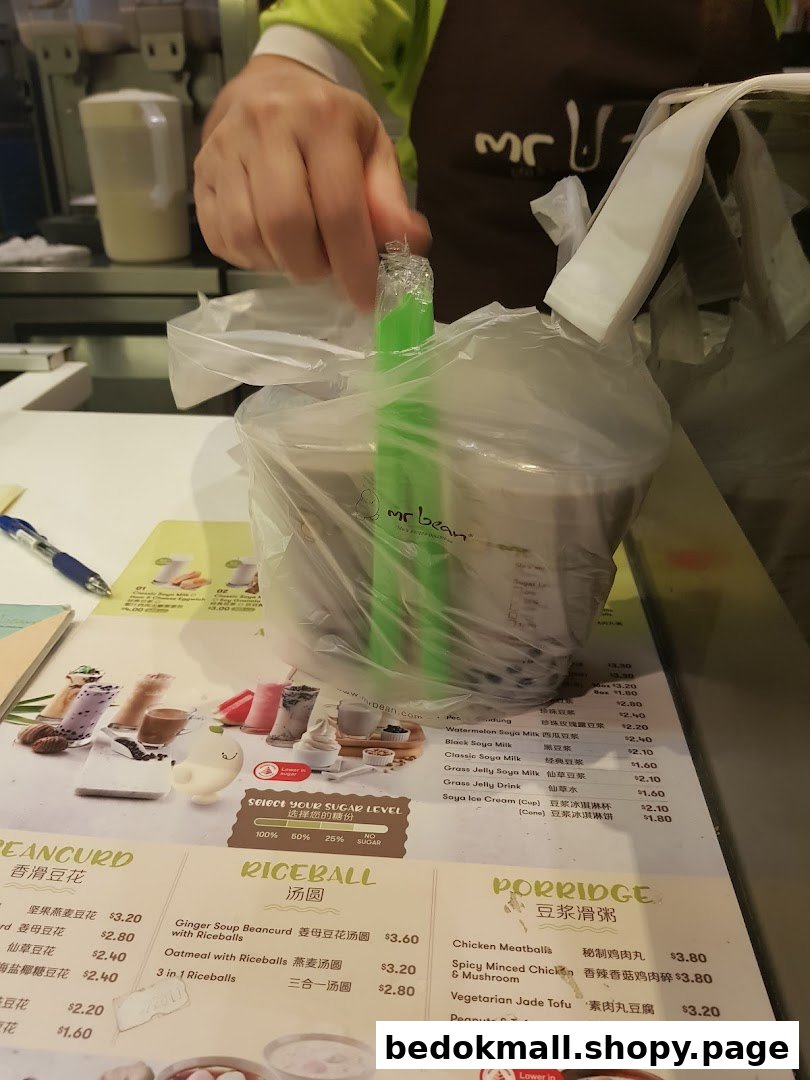 A hand holds a bagged order over a detailed menu at Mr Bean.