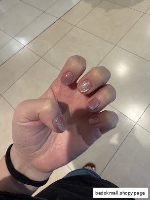 A hand with freshly manicured nails, some with glitter polish.
