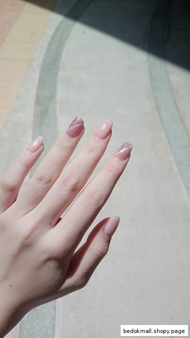 A hand displaying manicured nails, some with a glittery cat-eye design.