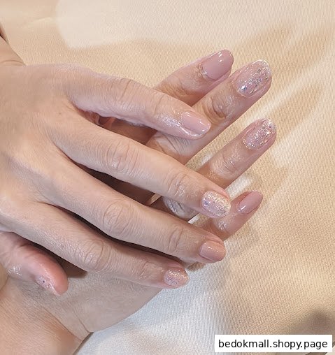 Close-up of hands with manicured nails, featuring pink and glitter designs.