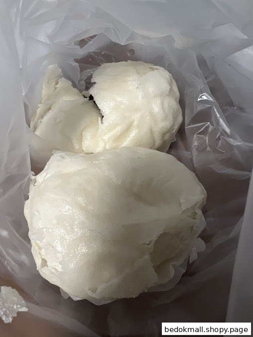 Two white buns in a clear plastic bag.