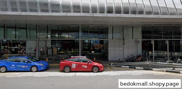 Exterior of a modern building with glass facade and two cars parked in front.