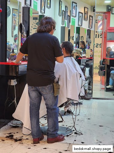 A barber cutting a customer's hair inside a barbershop.