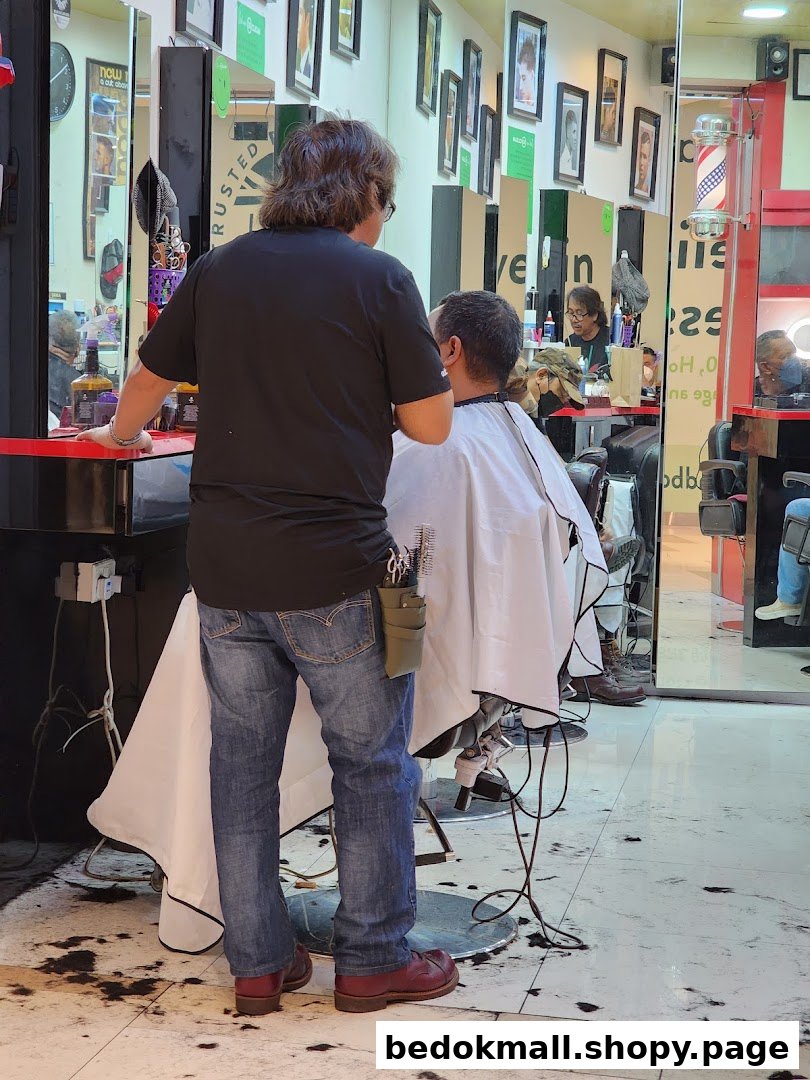 A barber cutting a customer's hair inside a shop.
