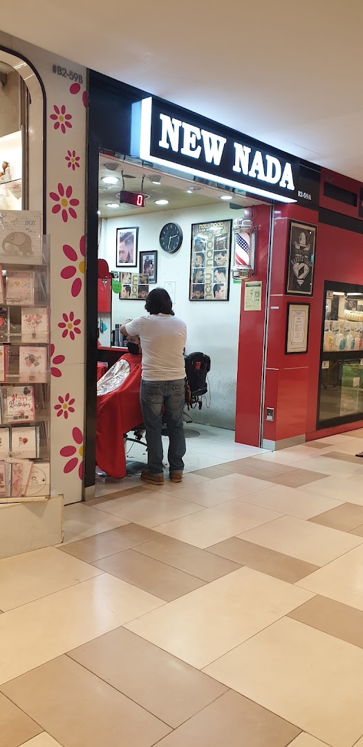 Barber cutting hair inside New Nada shop entrance.