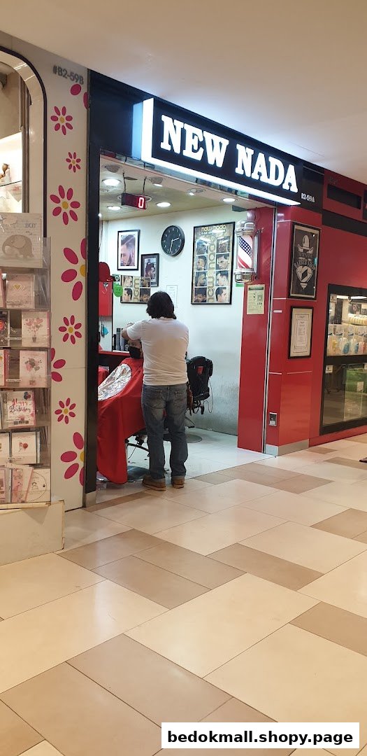 Barber cutting hair inside New Nada shop entrance.