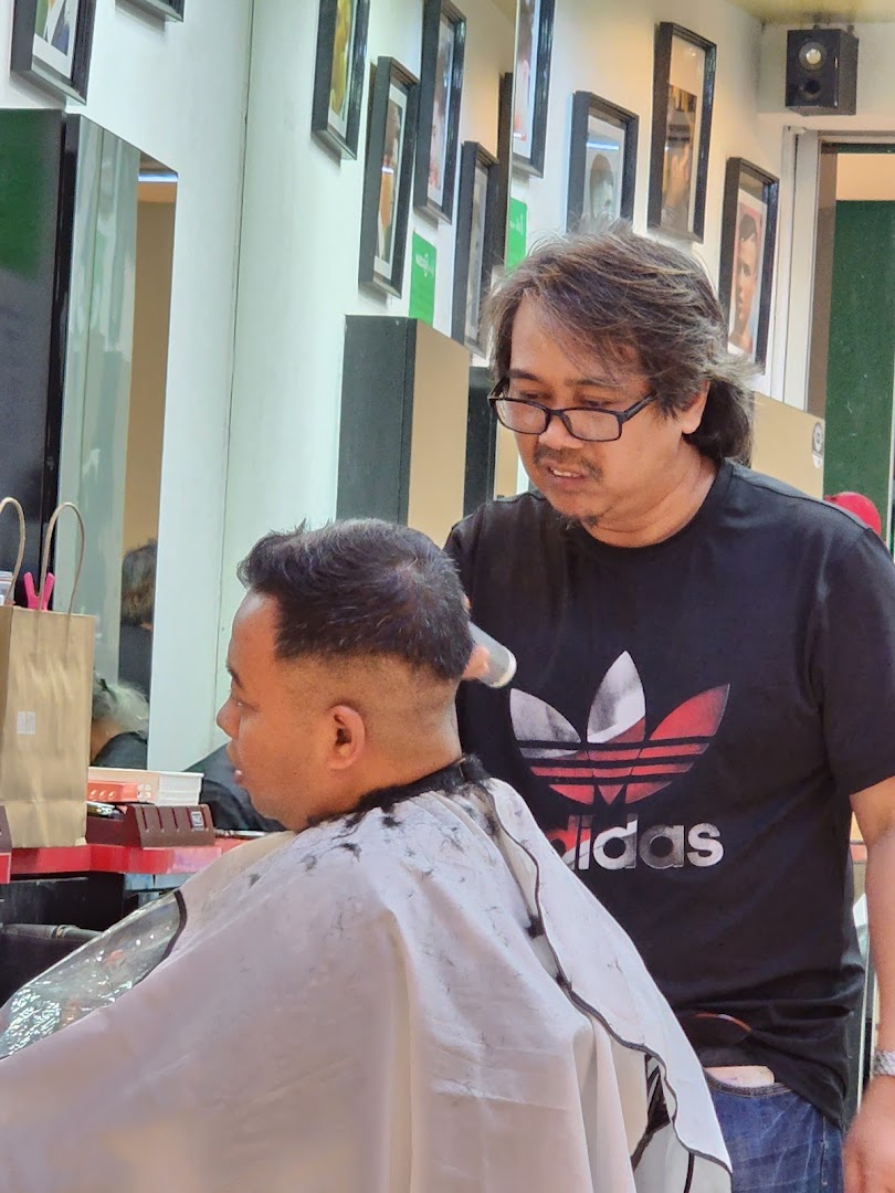A barber is cutting a customer's hair inside the shop.