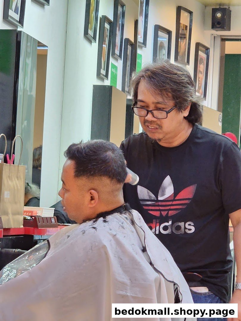 A barber is cutting a customer's hair inside the shop.