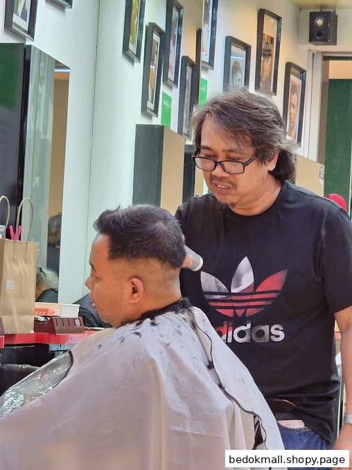 A barber cutting a customer's hair inside a barbershop.