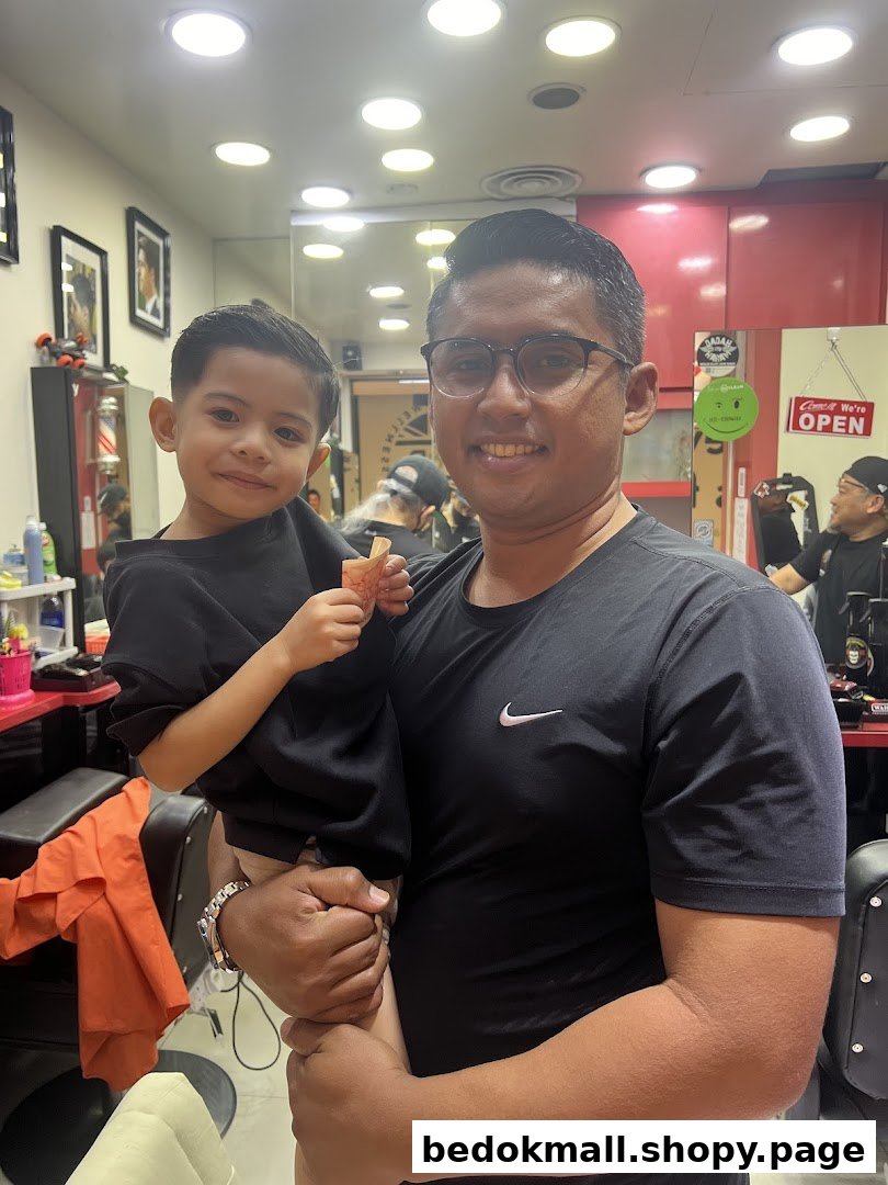 Adult and child inside a barber shop, smiling at the camera.