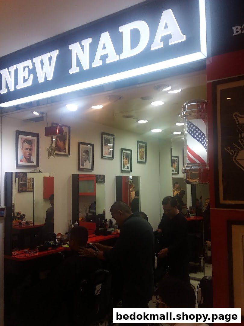 Interior view of a barber shop with customers getting haircuts and shop signage.