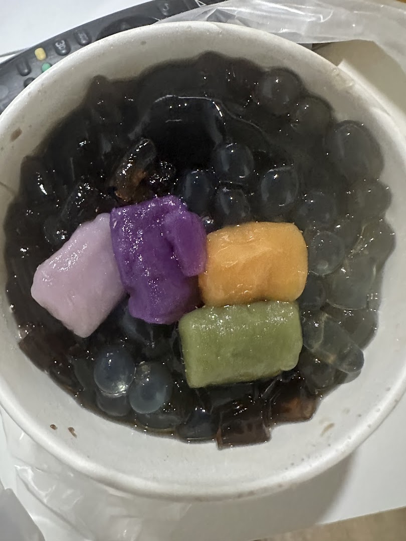 Bowl of dark dessert with colorful mochi and boba pearls.