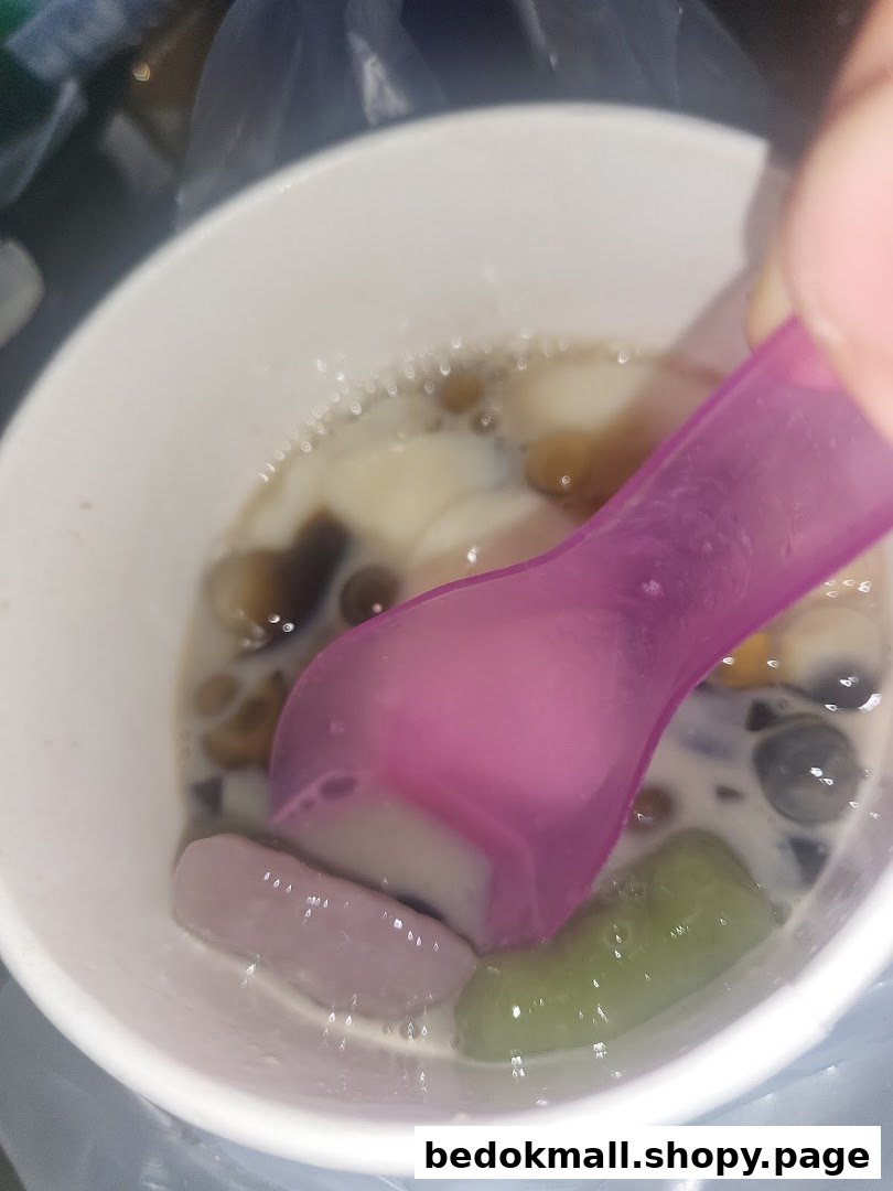 Close-up of a colorful dessert in a white cup with a purple spoon.
