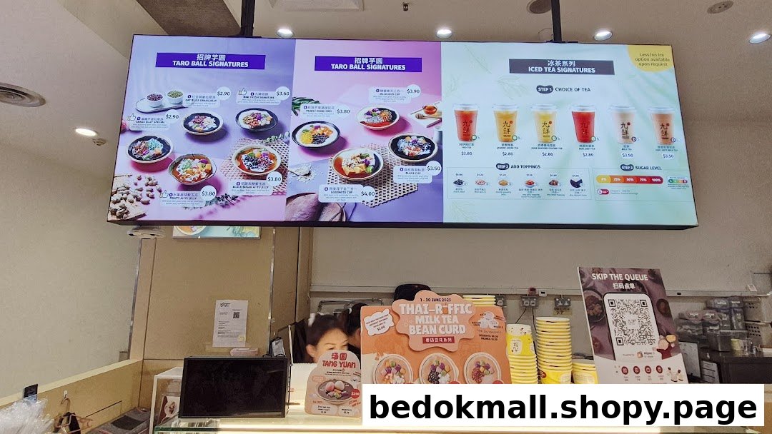 Digital menu board displaying various desserts and iced teas above a service counter.