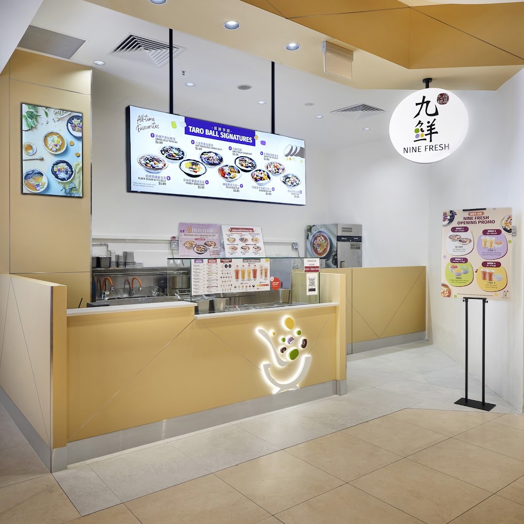 Dessert shop interior showing counter, digital menu, and promotional signs.