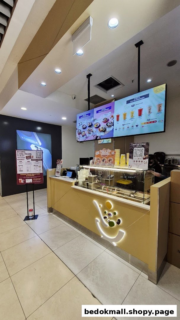 Interior view of a dessert shop counter with digital menus and staff.