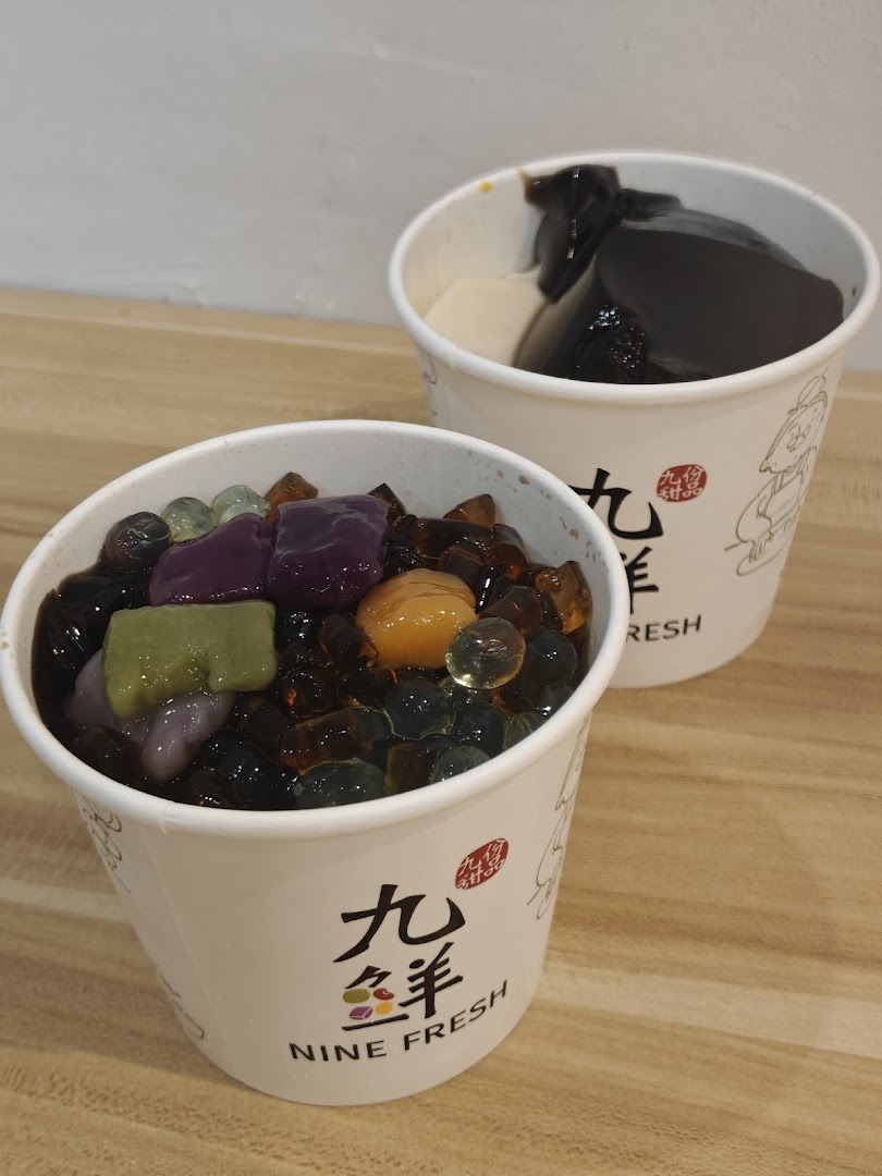 Two cups of colorful desserts with various toppings on a wooden surface.