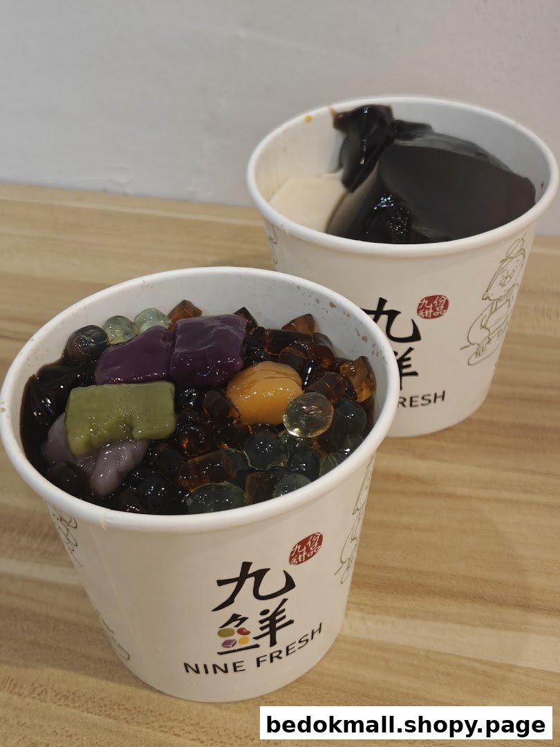 Two cups of colorful desserts with various toppings on a wooden surface.