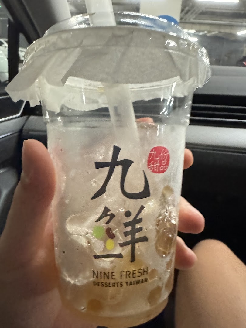 A hand holds a partially consumed Nine Fresh Desserts Taiwan drink cup.