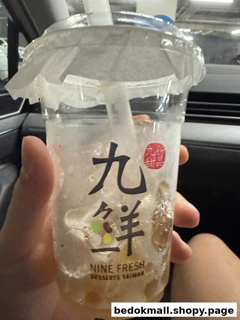 A hand holds a partially consumed Nine Fresh Desserts Taiwan drink cup.