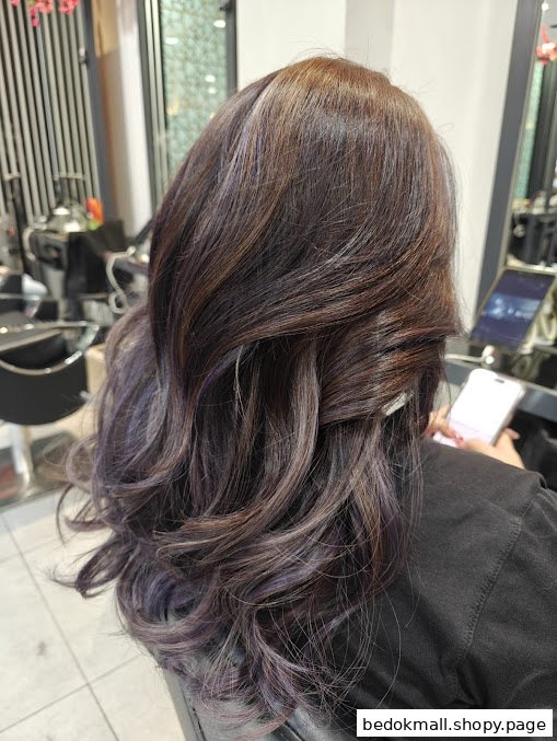 Back of a person's head with styled hair in a salon.