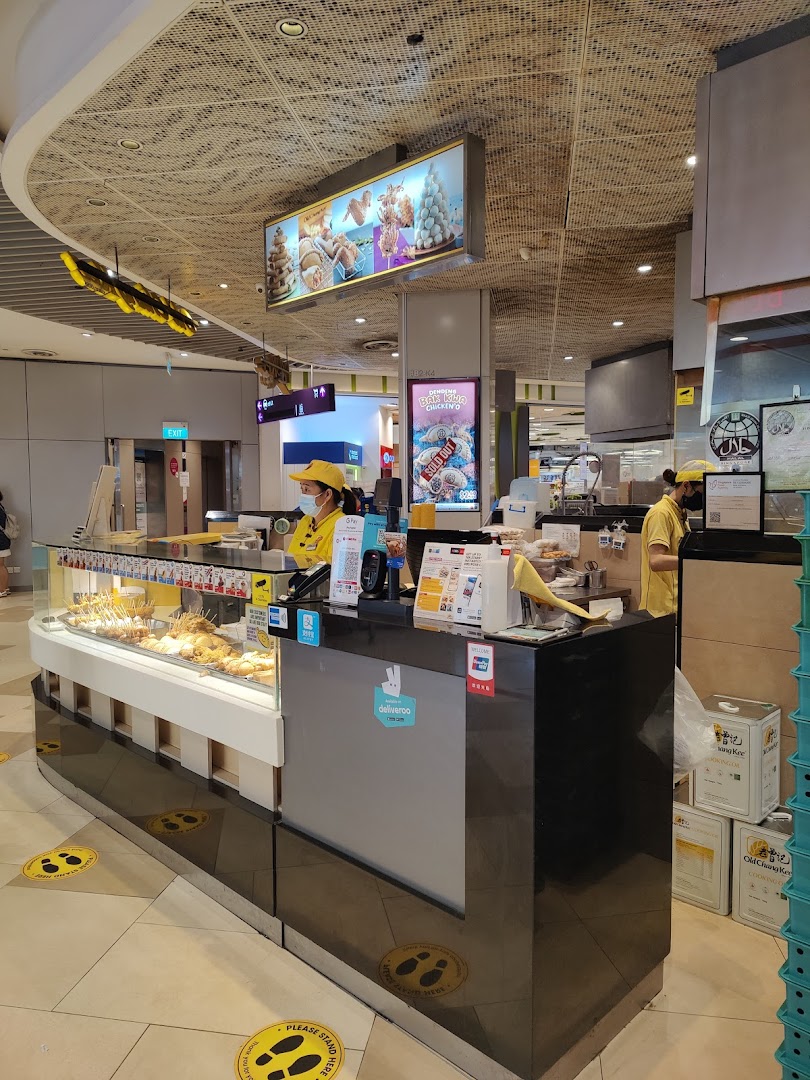 Interior view of a food stall with staff, counter, and food display.