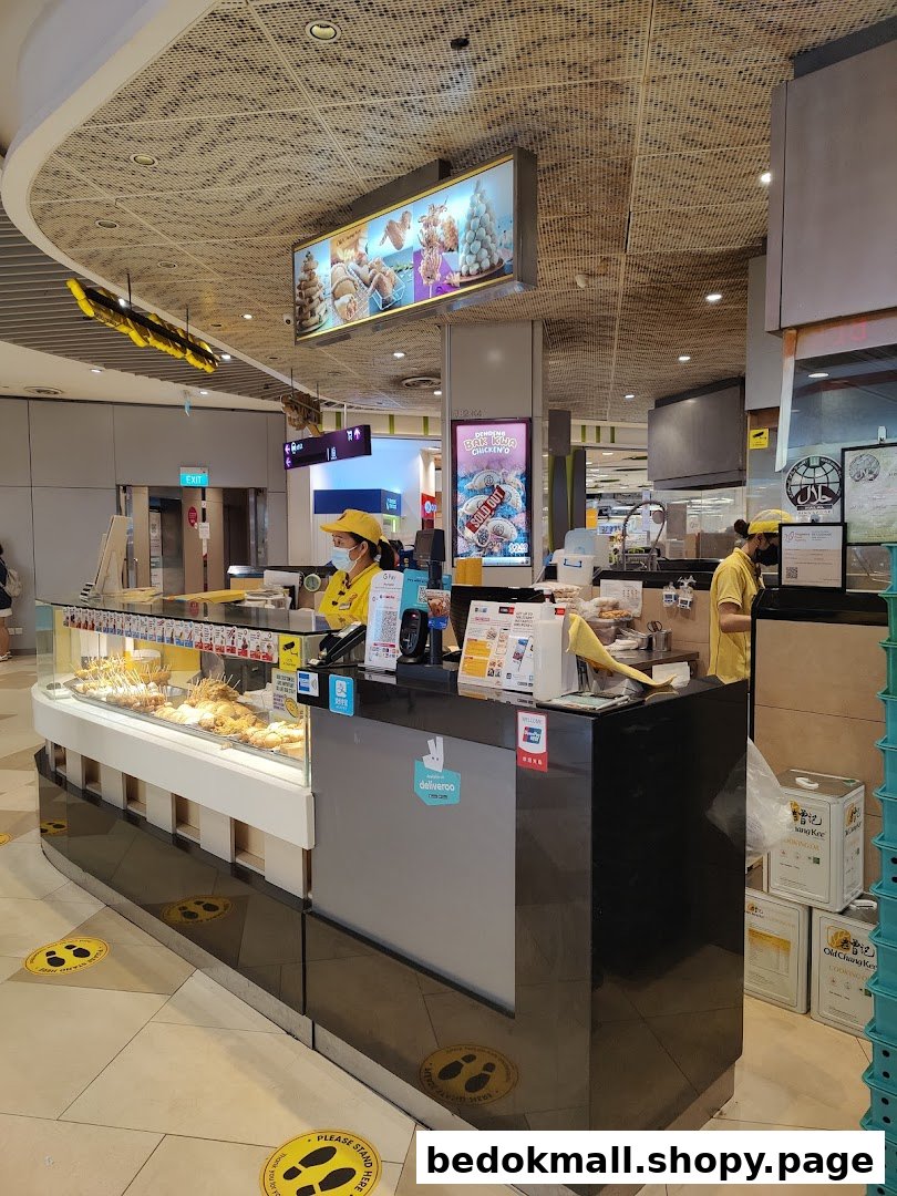 Interior view of a food stall with staff, counter, and food display.