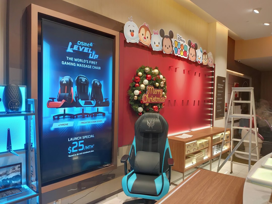 Shop interior with a gaming massage chair display, digital ad, and Christmas decor.