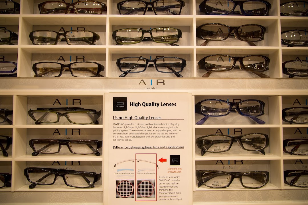 Display of eyeglasses on shelves with a sign explaining lens features.