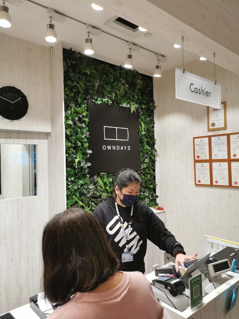 A staff member assists a customer at the cashier counter inside the shop.