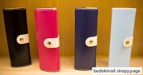 Four colorful cases, likely for glasses, displayed on a wooden shelf.