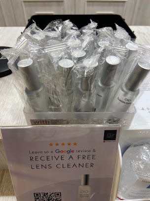 Display of packaged lens cleaners and a sign offering a free one for a review.
