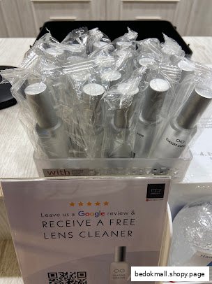 Display of packaged lens cleaners and a sign offering a free one for a review.