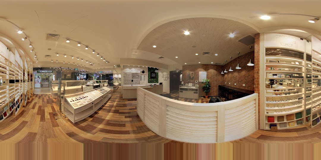 Panoramic interior view of a modern eyewear shop with display shelves and counter.