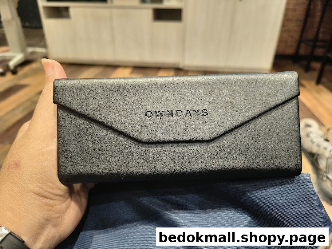 A person holds a black OWNDAYS eyeglasses case with the logo visible.
