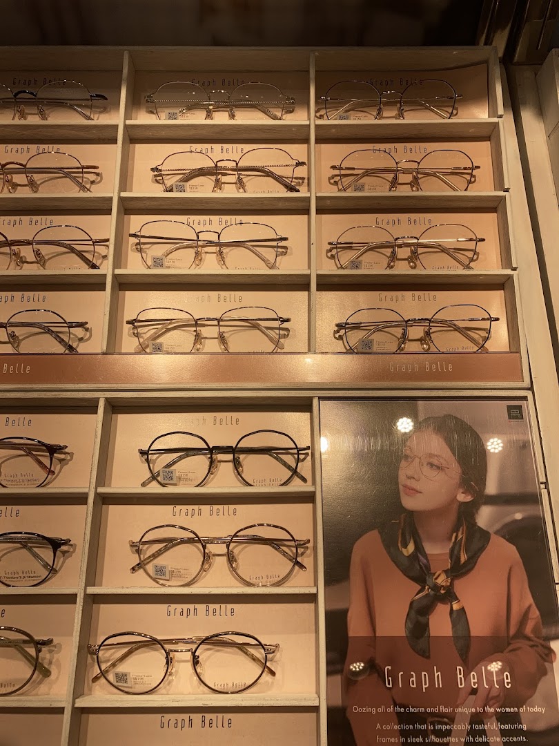Eyeglasses displayed on shelves with a promotional poster in a retail shop.