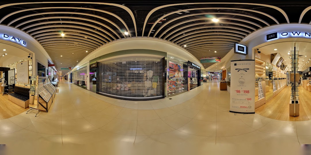 Wide-angle view of a mall corridor with multiple shop entrances, including OWNDAYS.