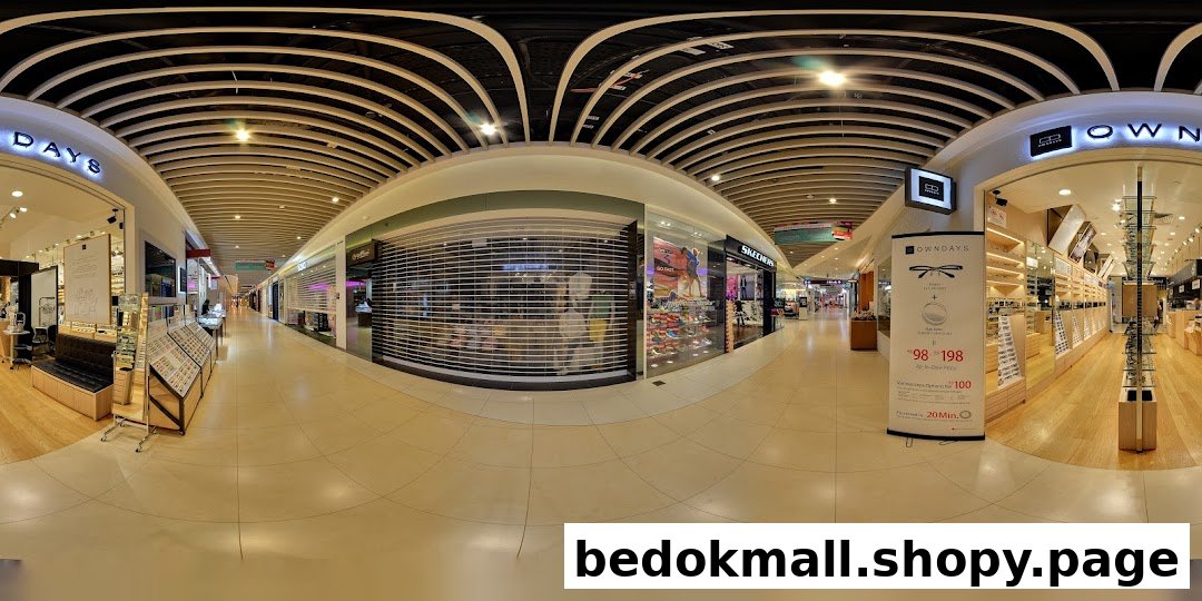 Wide-angle view of a mall corridor with multiple shop entrances, including OWNDAYS.