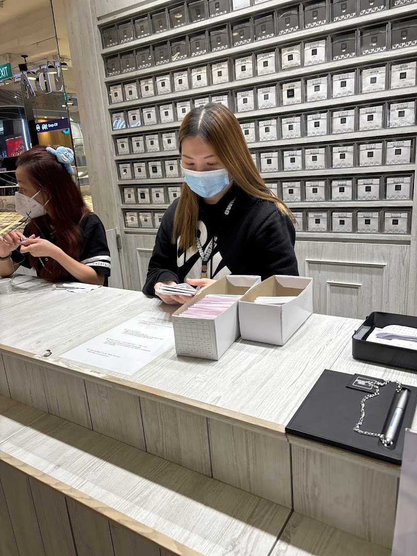 Two people at a counter inside a shop with many small boxes on the wall.