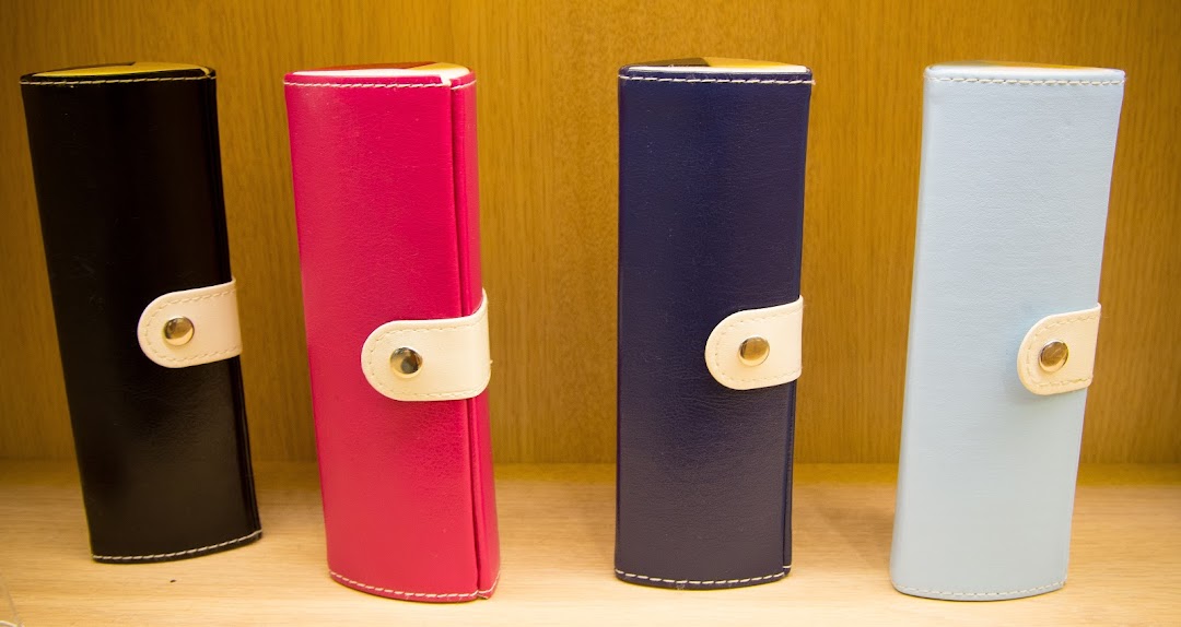 Four colorful cases, likely for glasses, displayed on a wooden shelf.