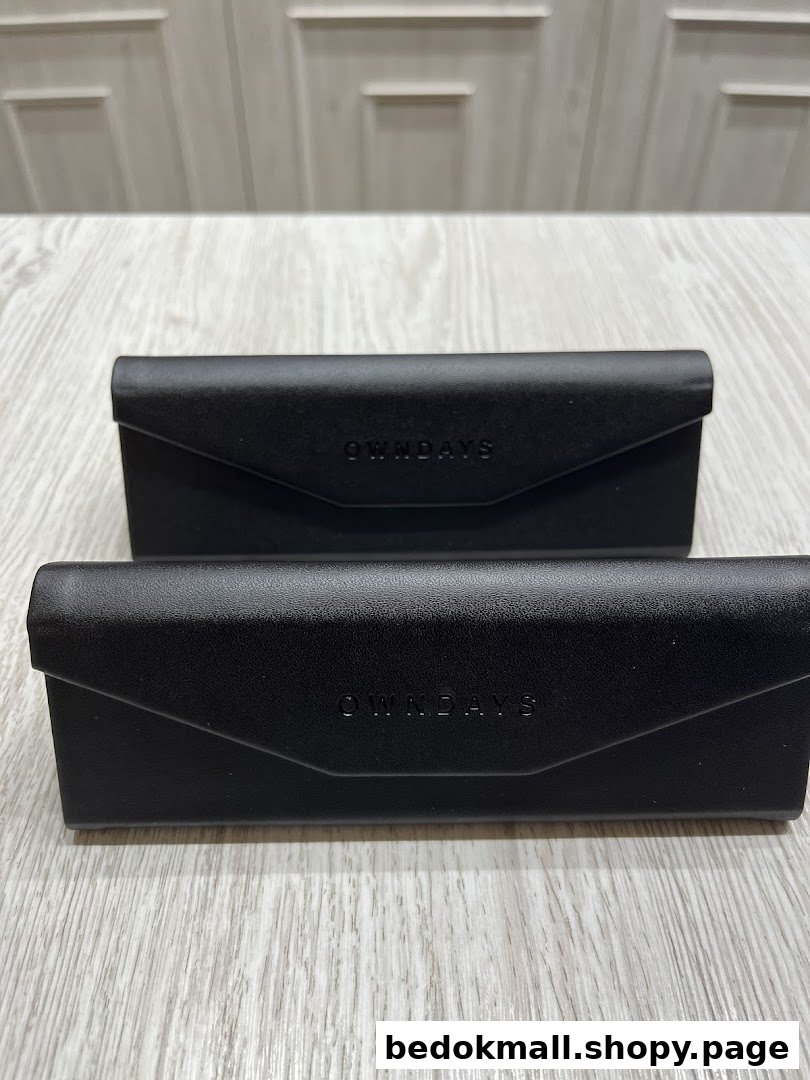 Two black OWNDAYS eyewear cases on a light wooden surface.