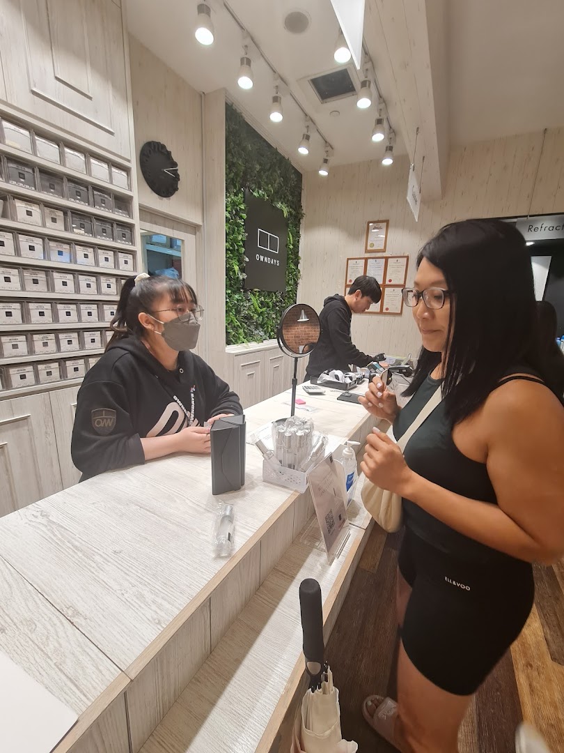 Customer interacting with staff at a counter inside an OWNDAYS shop.