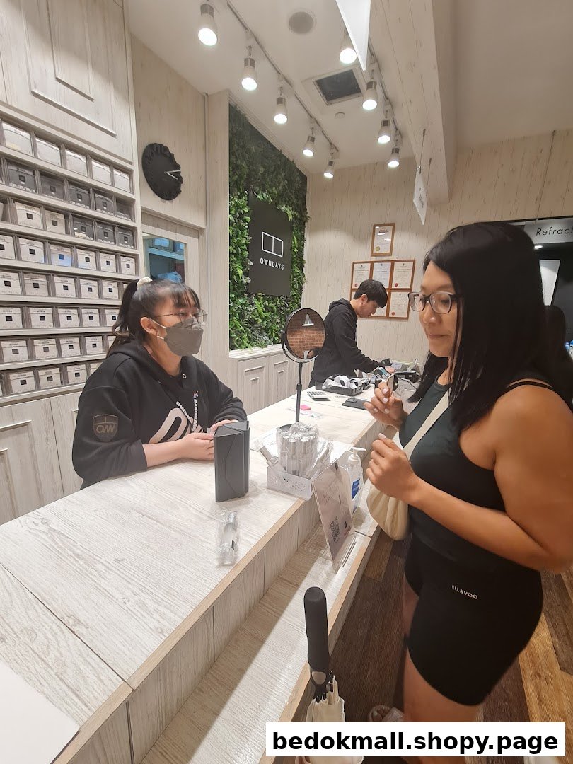 Customer interacting with staff at a counter inside an OWNDAYS shop.